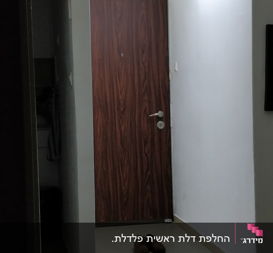 דלת עץ עם ידית מתכת במסדרון מואר